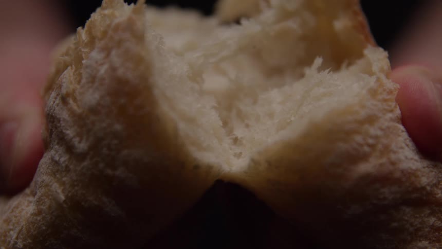 Extreme close up of a person splitting fresh baked bread in half