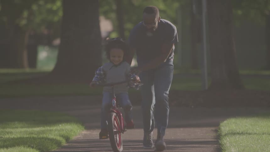 Father teaches his son to ride a bicycle in the park