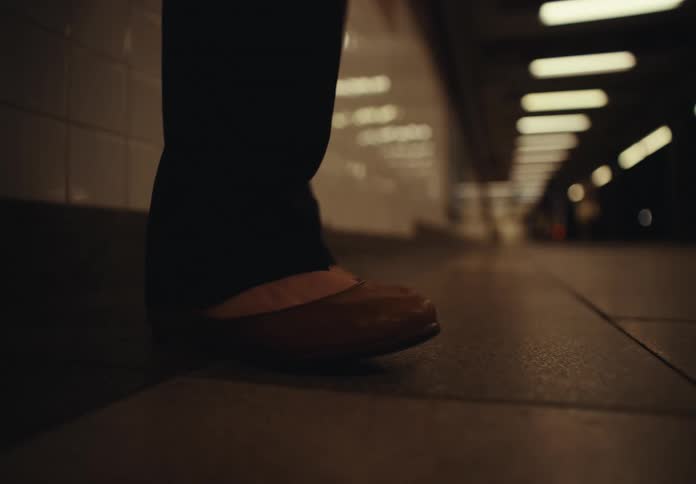 Woman standing near a tiled wall taps a foot