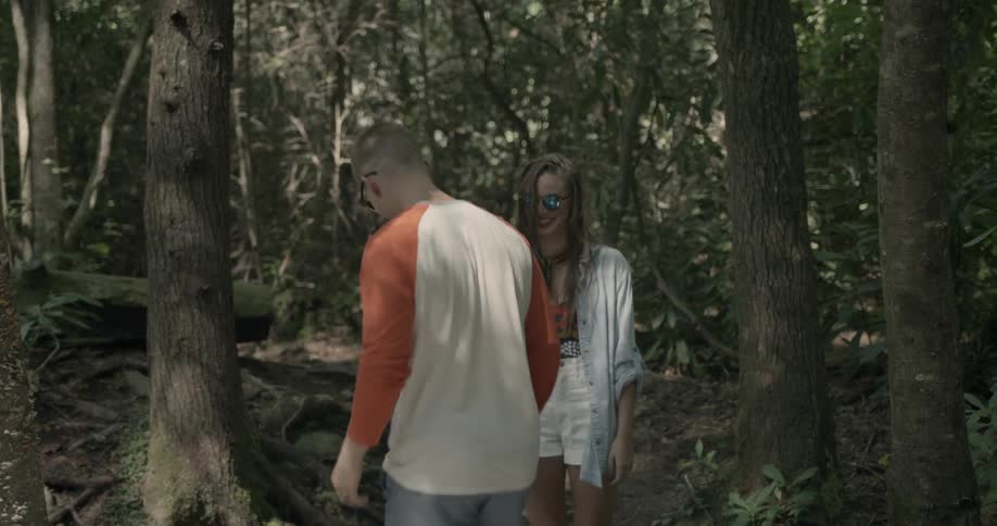 Two people hike in the woods, the man gives a piggyback ride halfway