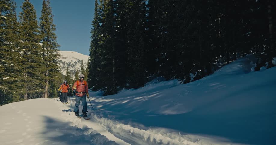 People are hiking through the snow on a mountain pass