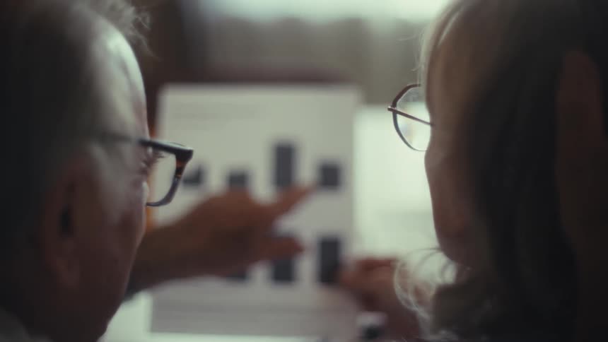 A man talks with a woman while pointing at a piece of paper