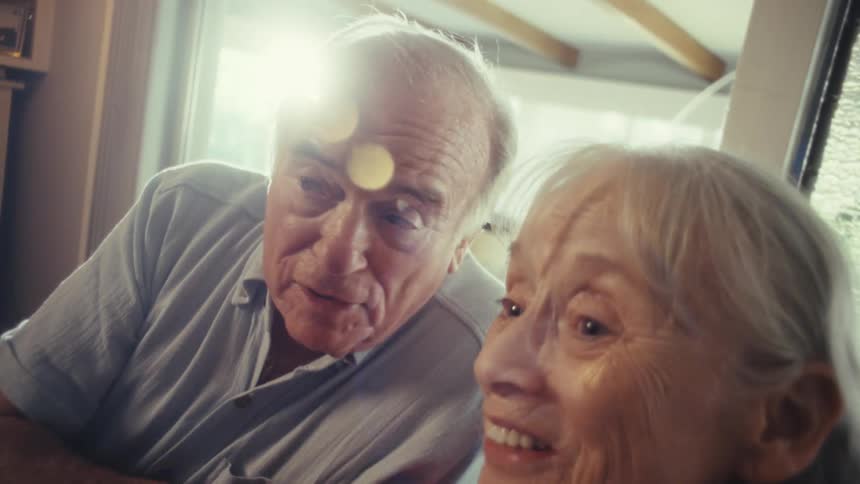An elderly couple sing into a microphone happily