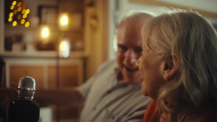 A couple are singing and laughing with a microphone