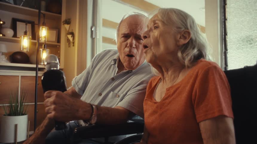 The man holds the microphone as he and a woman sing