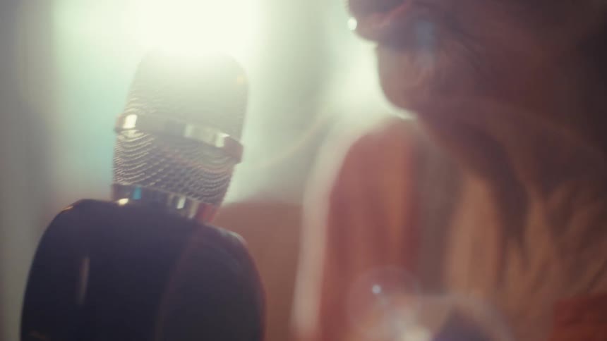 The woman sings into the microphone on a sunny day