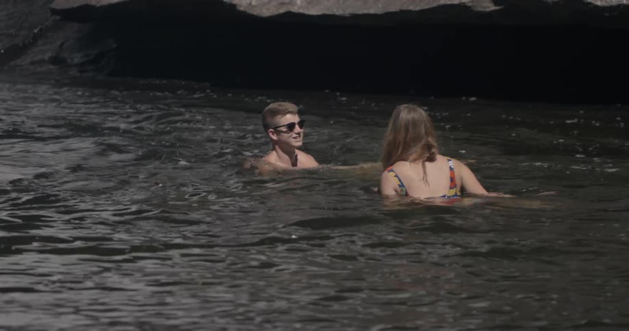 A man and woman play in the water and talk