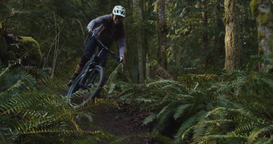 The woman does a turn on the trail in the forest on her mountain bike