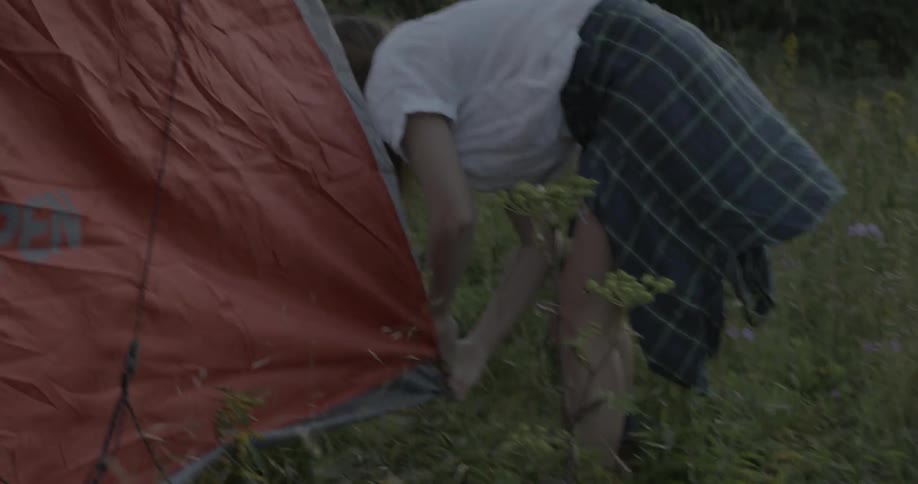 A woman is setting up a tent on a very windy day
