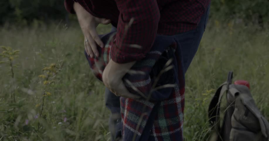 A man leans forward rolling up a blanket