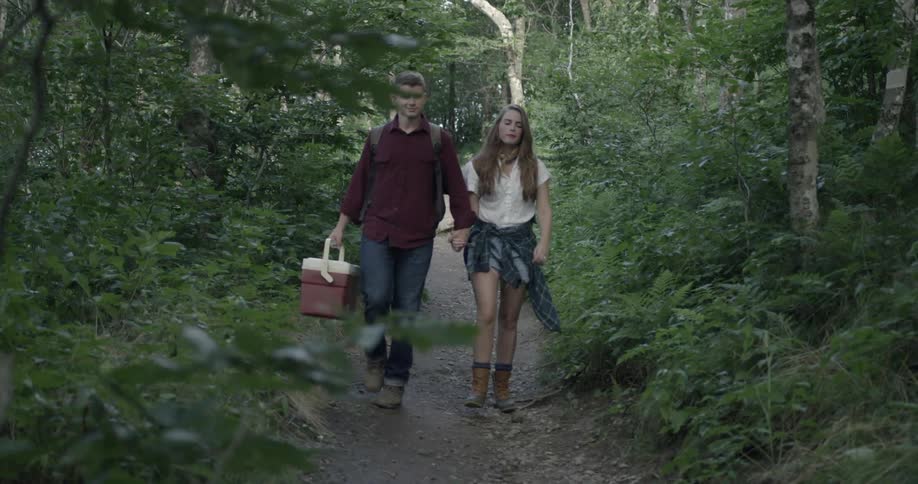 A couple hold hands walking down a trail