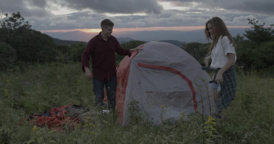 Two people set up a tent on a windy day