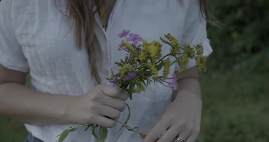 Woman outside holding bouquet of purple and yellow wildflowers