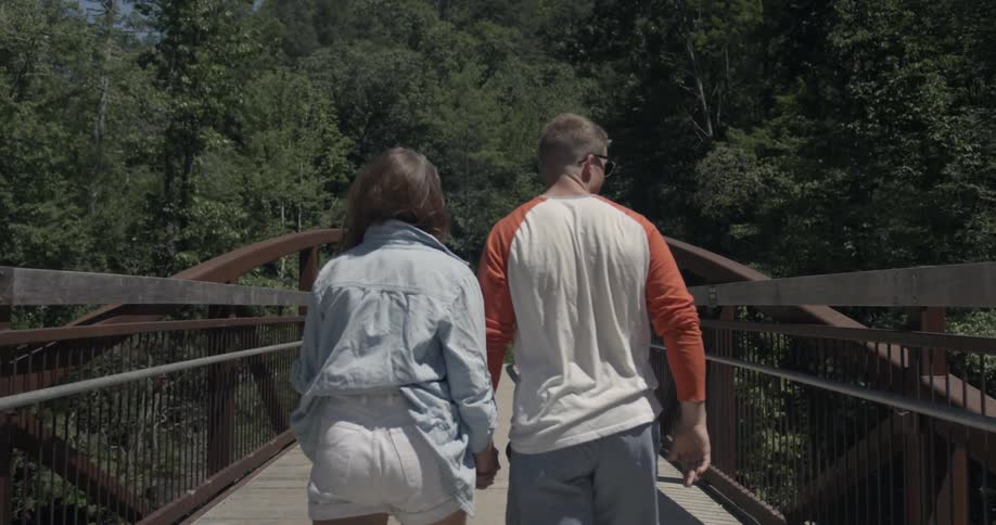 A man and woman walk across a bridge