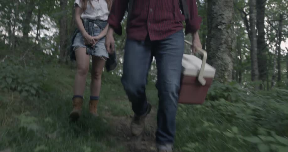 Man and woman walking in forest with cooler