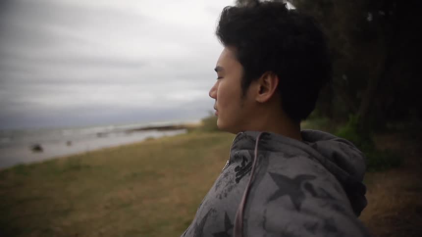 Man leans back and looks at the beach on a cloudy day