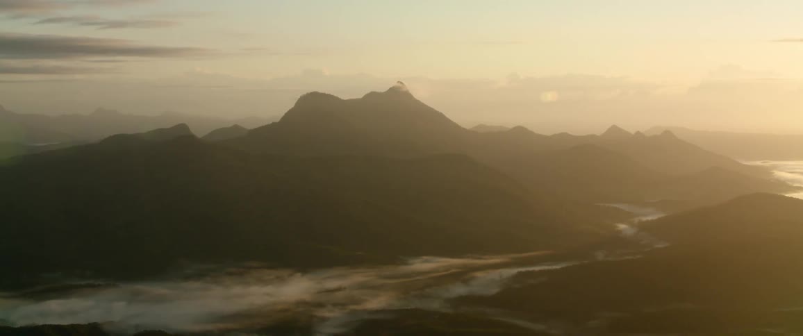 Fog rolling over valley at the base of the mountain at sunrise