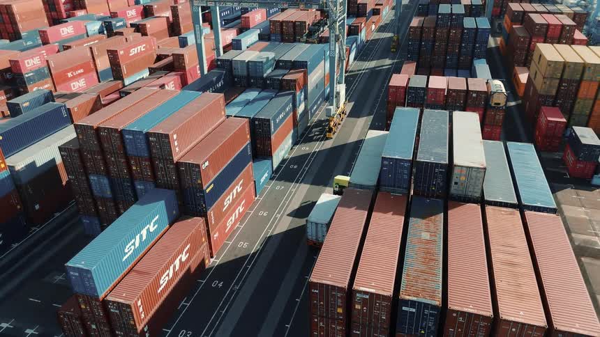 This video provides a closeup aerial view of a busy shipping port the footage shows rows and rows of shipping containers stacked high with a truck moving through a designated lane