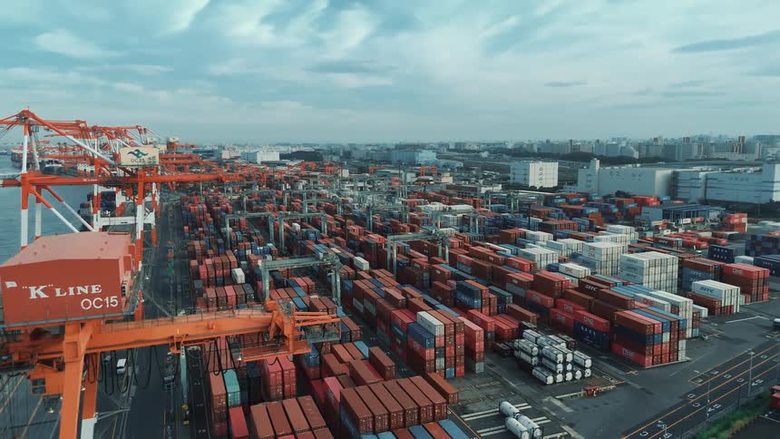 Orange cranes operate over a vast area filled with organized containers at the port