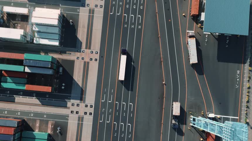 Trucks driving on the roads inside a large cargo shipping container depot