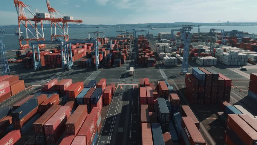 Trucks drive past the cargo containers in the harbor
