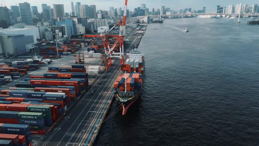 Aerial view of a harbor with cranes and cargo containers by the waterfront