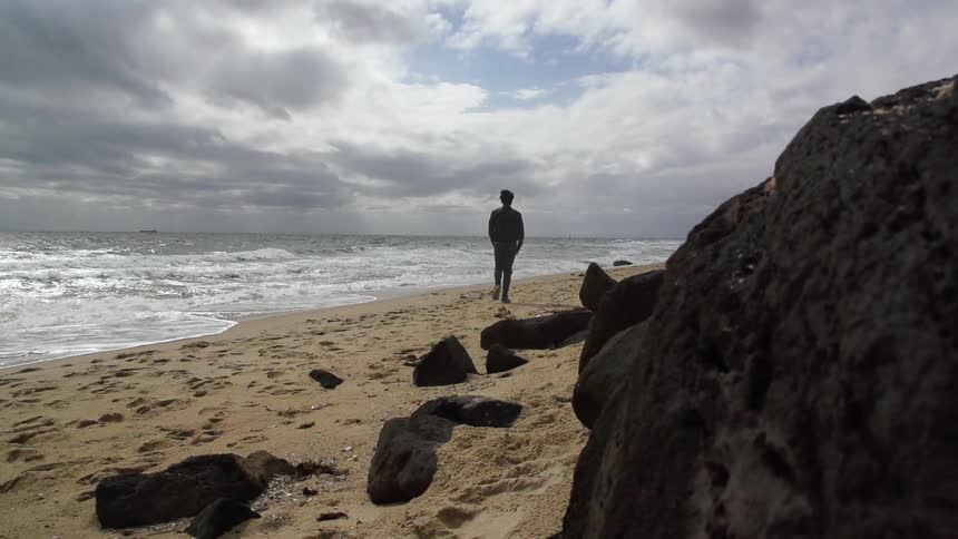 Person walks along a rocky beach