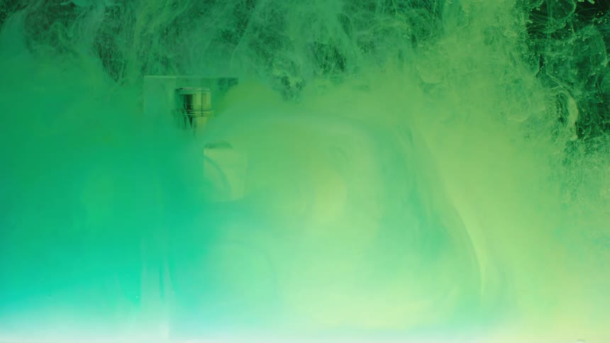 In the video vibrant green and yellow ink flows and swirls in a tank of water the pigments move and spread creating an abstract and dynamic visual effect