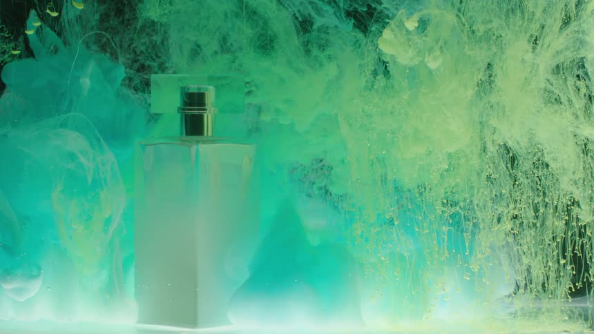 In the video a perfume bottle stands tall in the center of a glass tank surrounded by a mesmerizing mix of blue and green ink the ink creates a dynamic and surreal underwater scene as it swirls and billows around the bottle