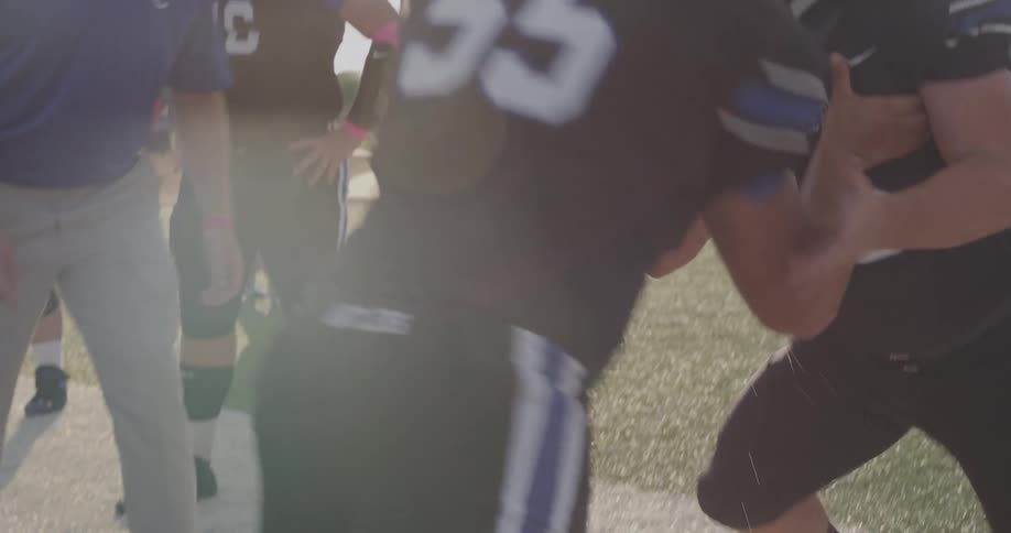 This video shows two football players the player in the foreground wearing a black jersey with the number 55 is in a crouched stance the second player wearing a white jersey with the number 99 is also in a crouched stance facing the first player