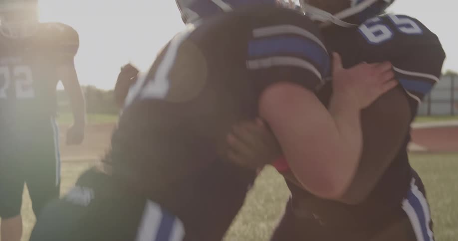 The video shows a closeup of two football players in a crouched stance facing each other one player wears a black jersey with the number 51 and the other wears a black jersey with the number 65 in the background there is another line of players in th