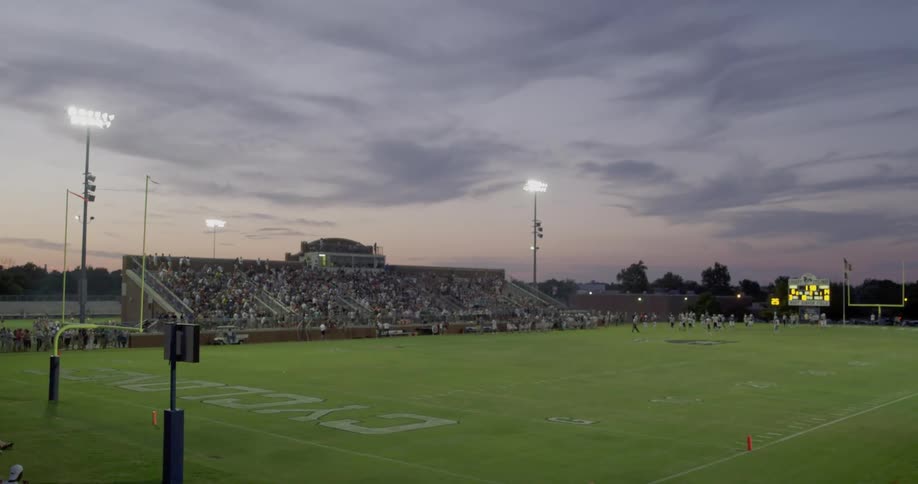 Fans fill the stadium during an evening american football game