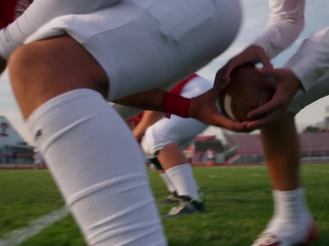 Player snapping the a ball to quarterback for a running play in american football
