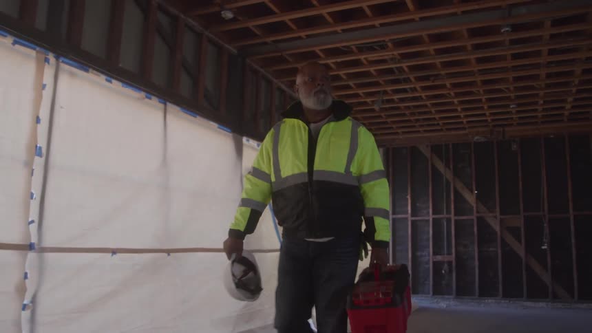 Man walking with a toolbox on a construction site