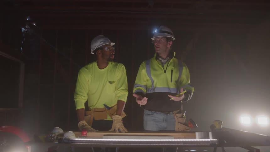 Two men wearing helmets working on a construction site