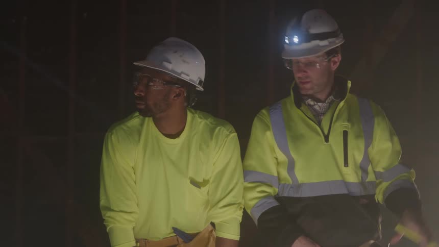 The construction workers talk and point