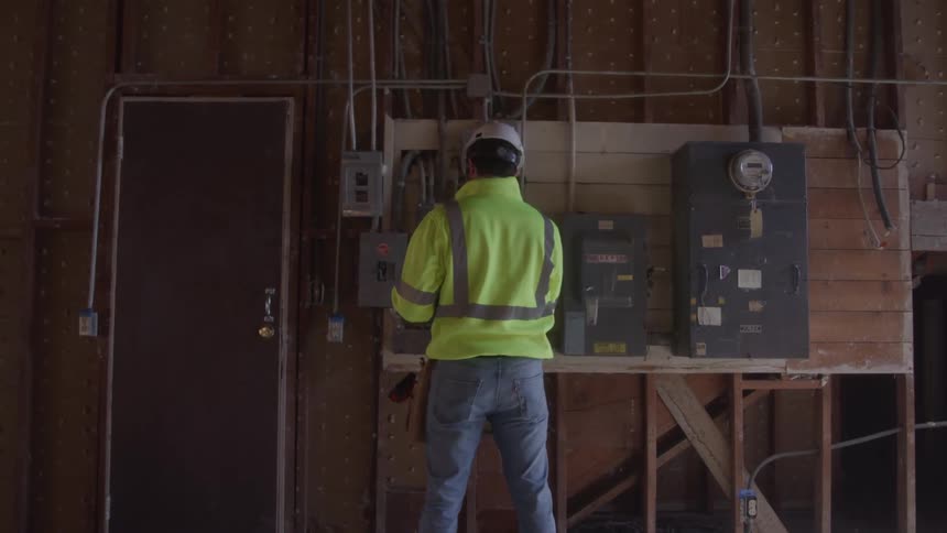 Engineer wearing a helmet and vest checking the electrical part of a construction site