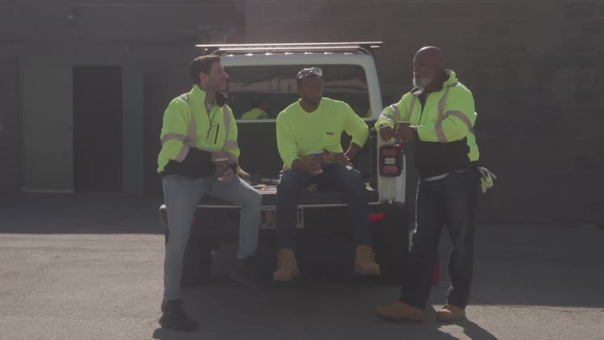 Three uniformed workers near a car talking