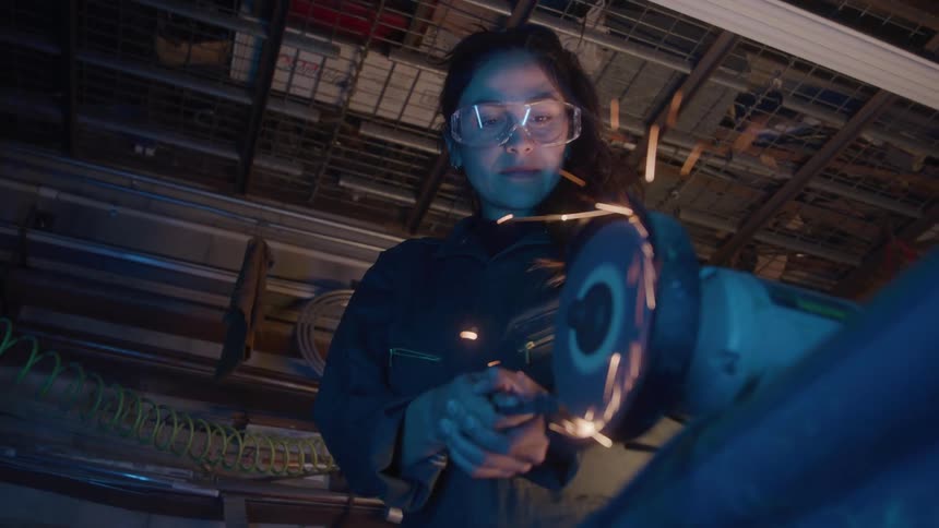 Woman wearing safety glasses uses a grinder releasing sparks