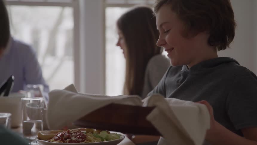 Smiling boy holding a bread basket at the table