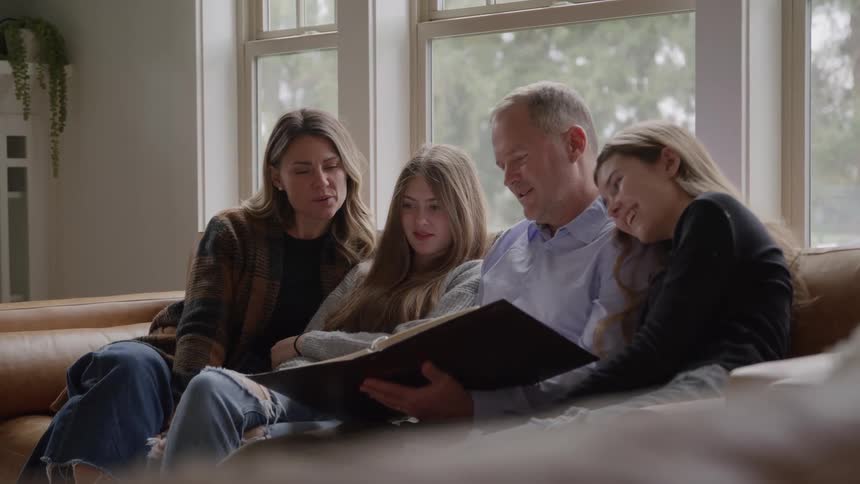 Family sitting on the couch looks at a photo album together
