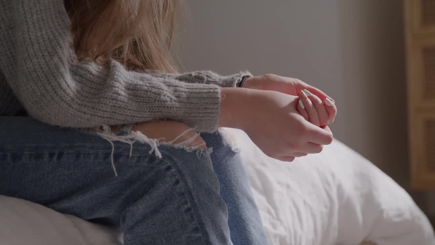 Intertwined hands resting on the lap