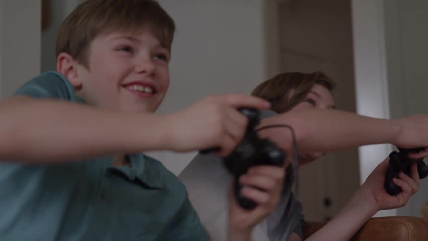 Two smiling boys playing video games together