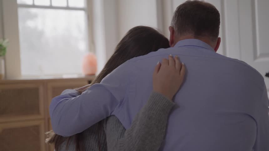 Man and young woman hug while sitting close in a moment of support