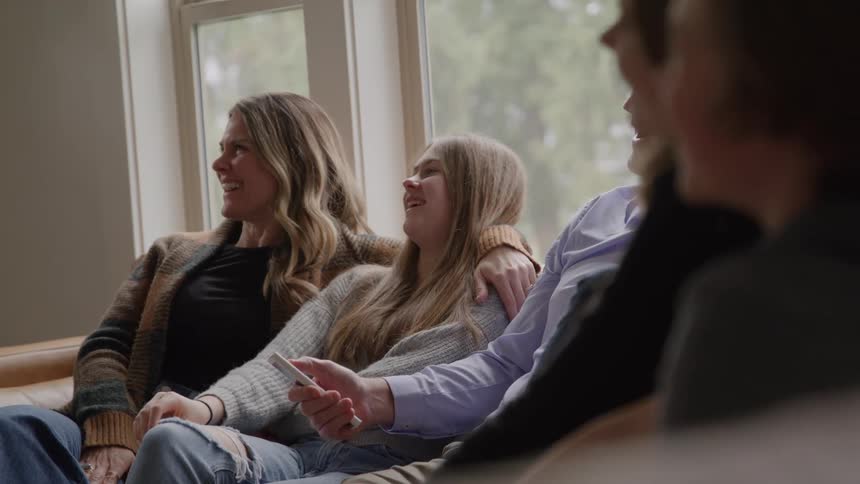 Family gathered on the couch smiling while watching together
