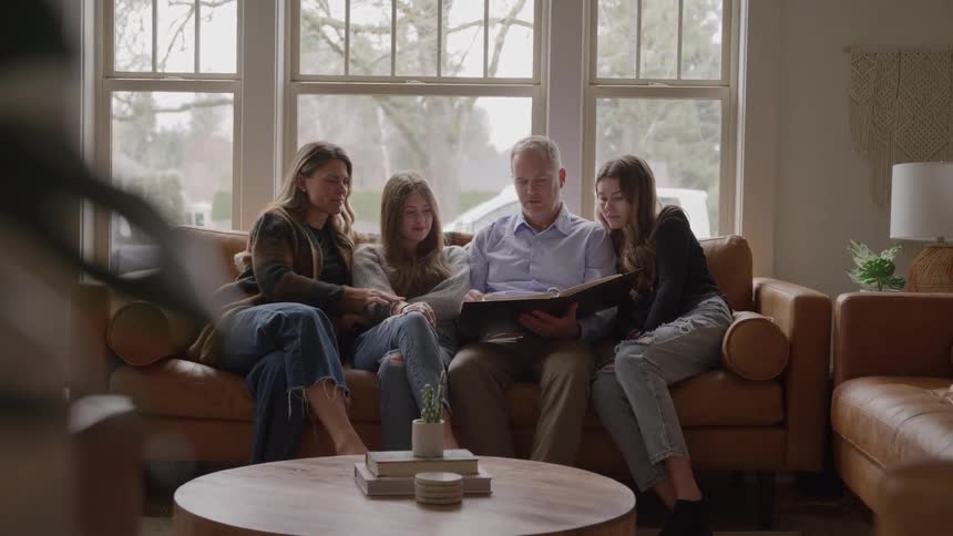 Family gathered on the couch flips through a photo album together