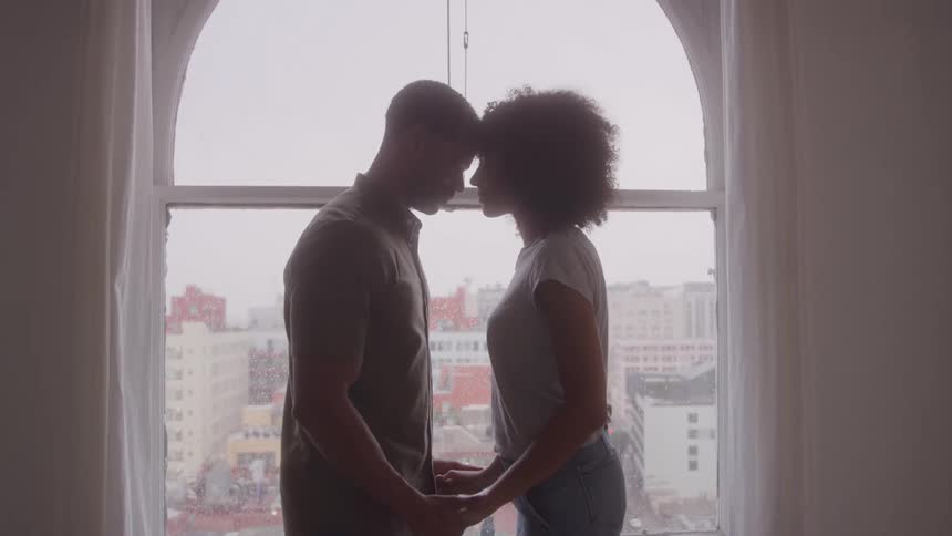 A man and woman are holding hands and leaning heads together