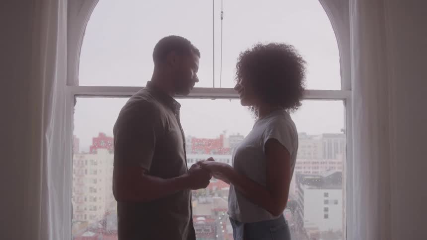 A man and woman hold hands by the window