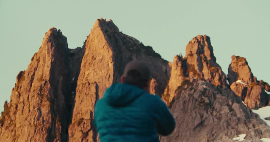 Person in a blue jacket photographs rocky formations lit by the sun