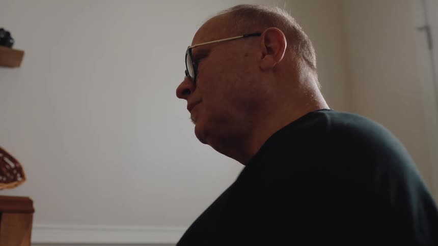 Man wearing glasses plays the piano with a focused expression